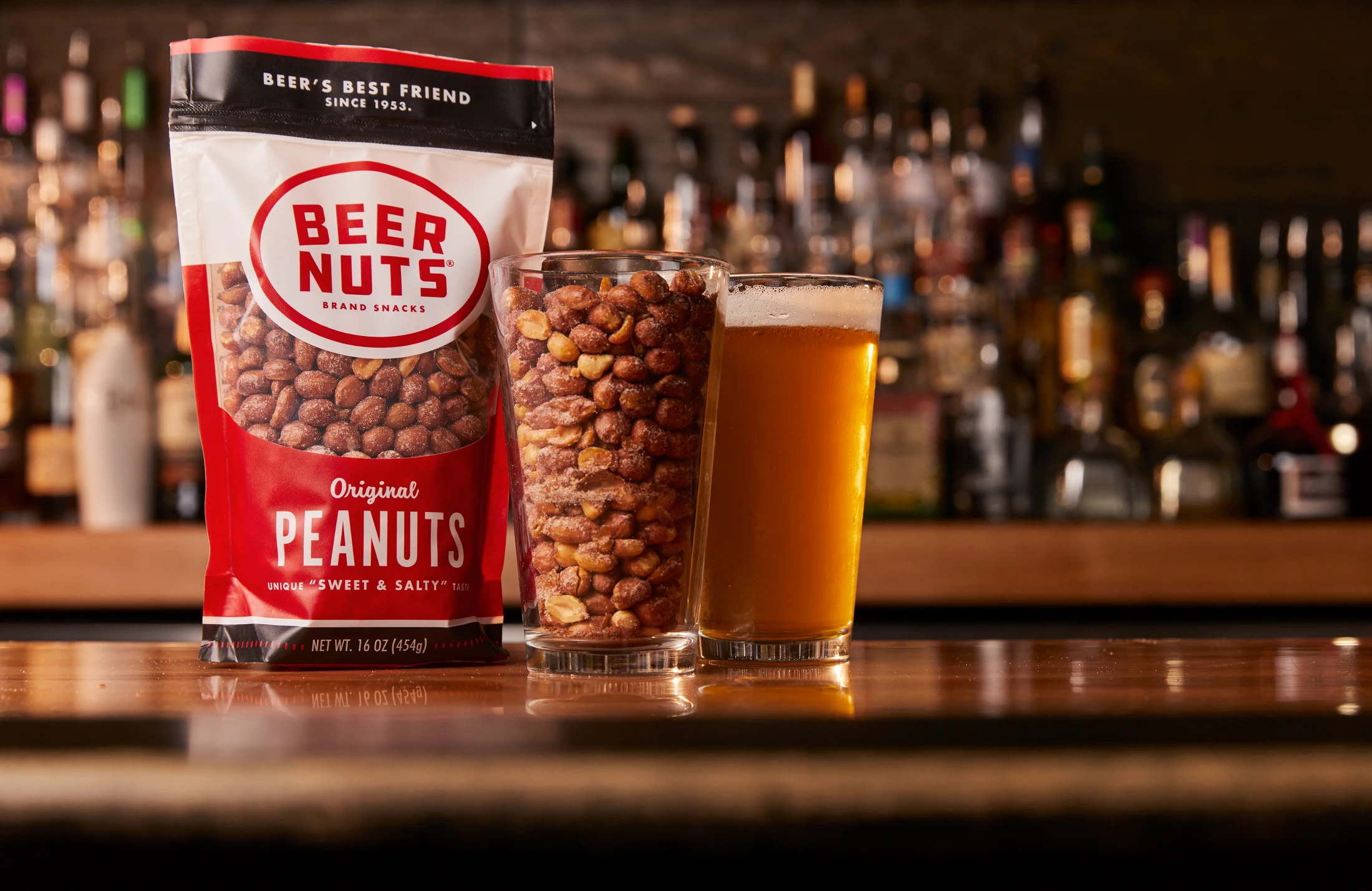 Beer Nuts peanuts on a bar with a glass of beer.