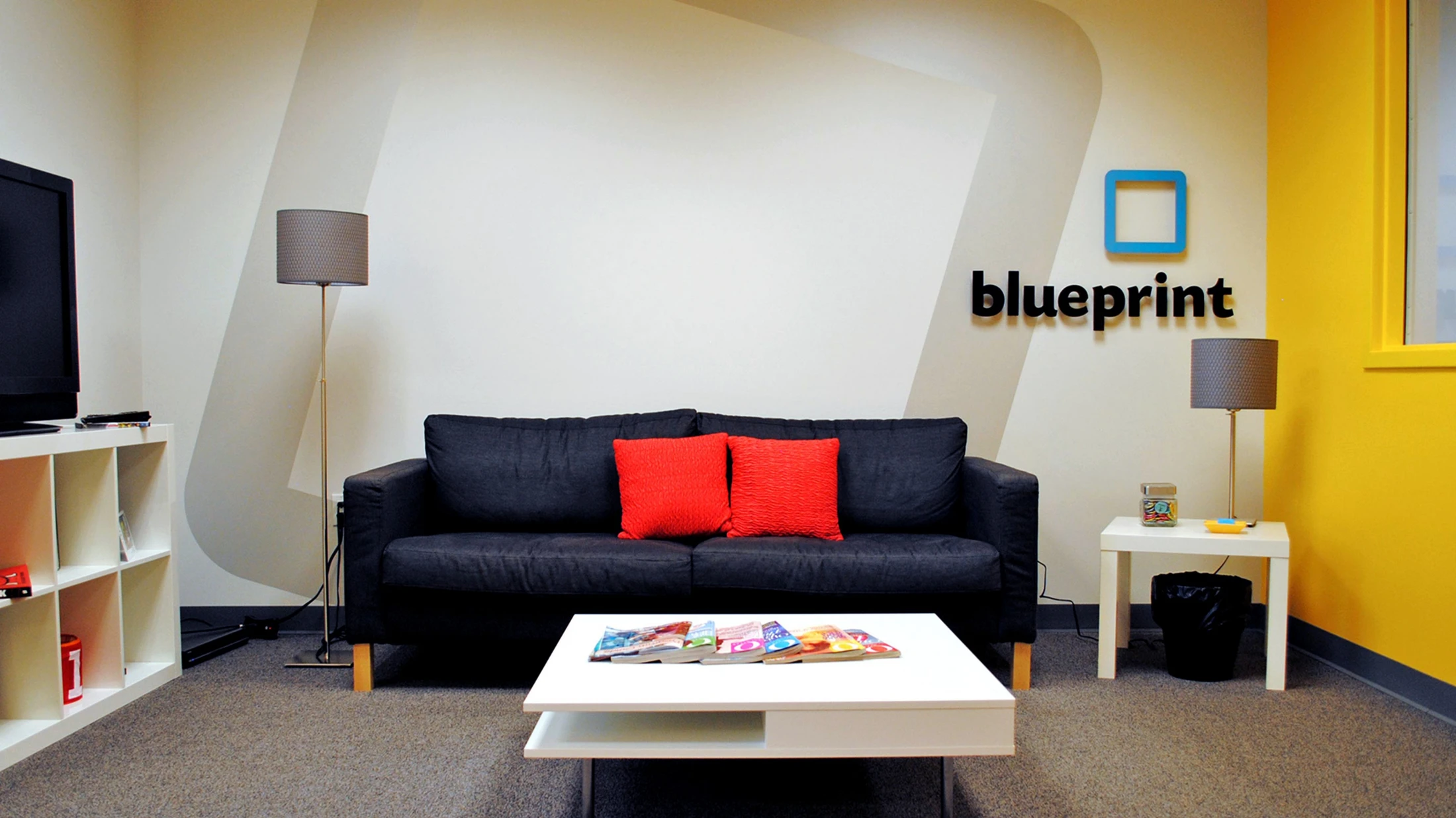 A living room with a blueprint logo on the wall.