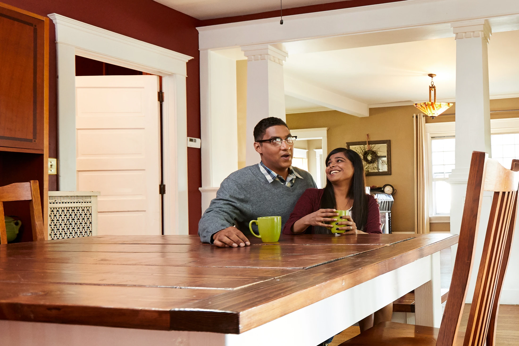 A man and woman sitting at a table in a kitchen.