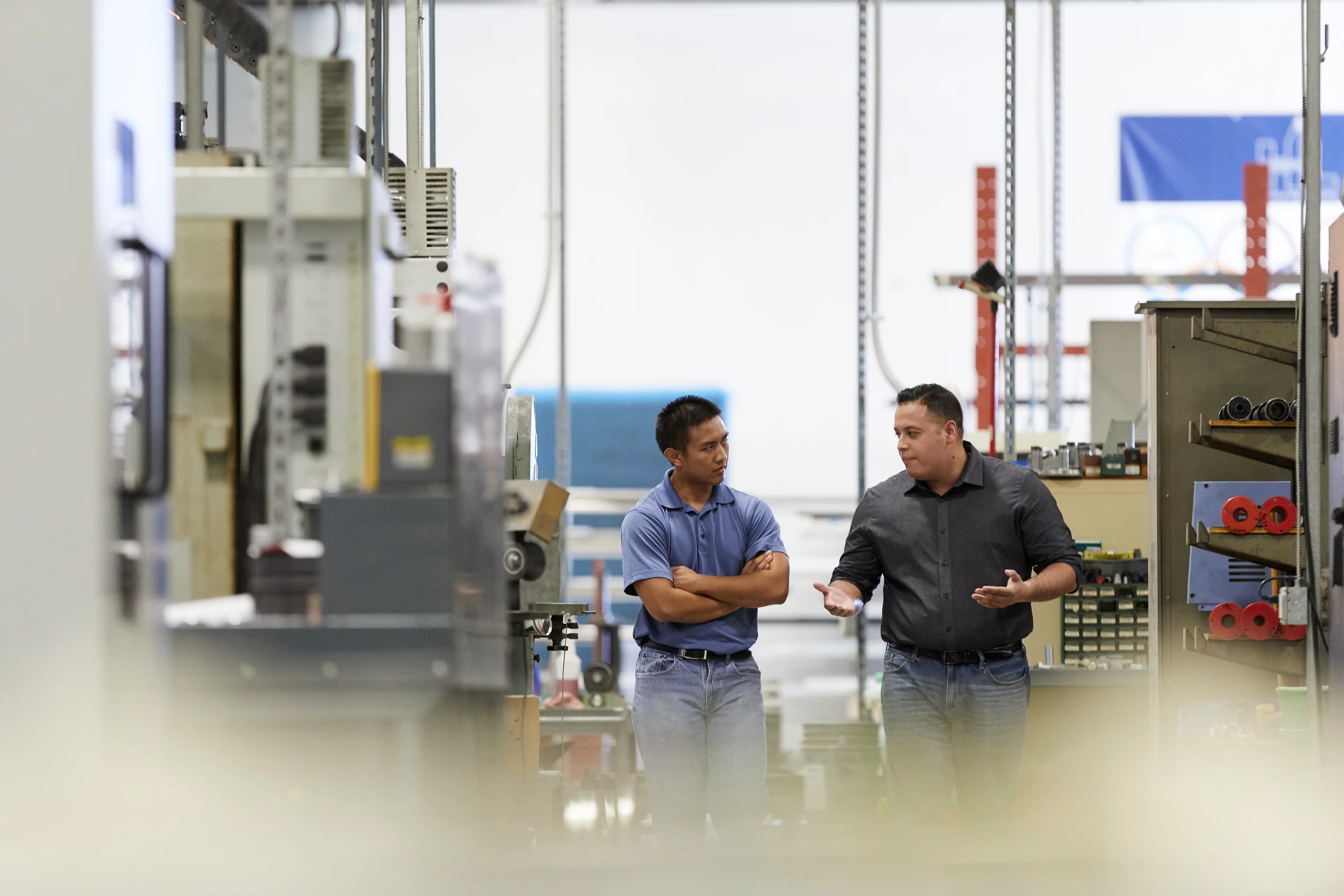 Two men in a factory talking to each other.