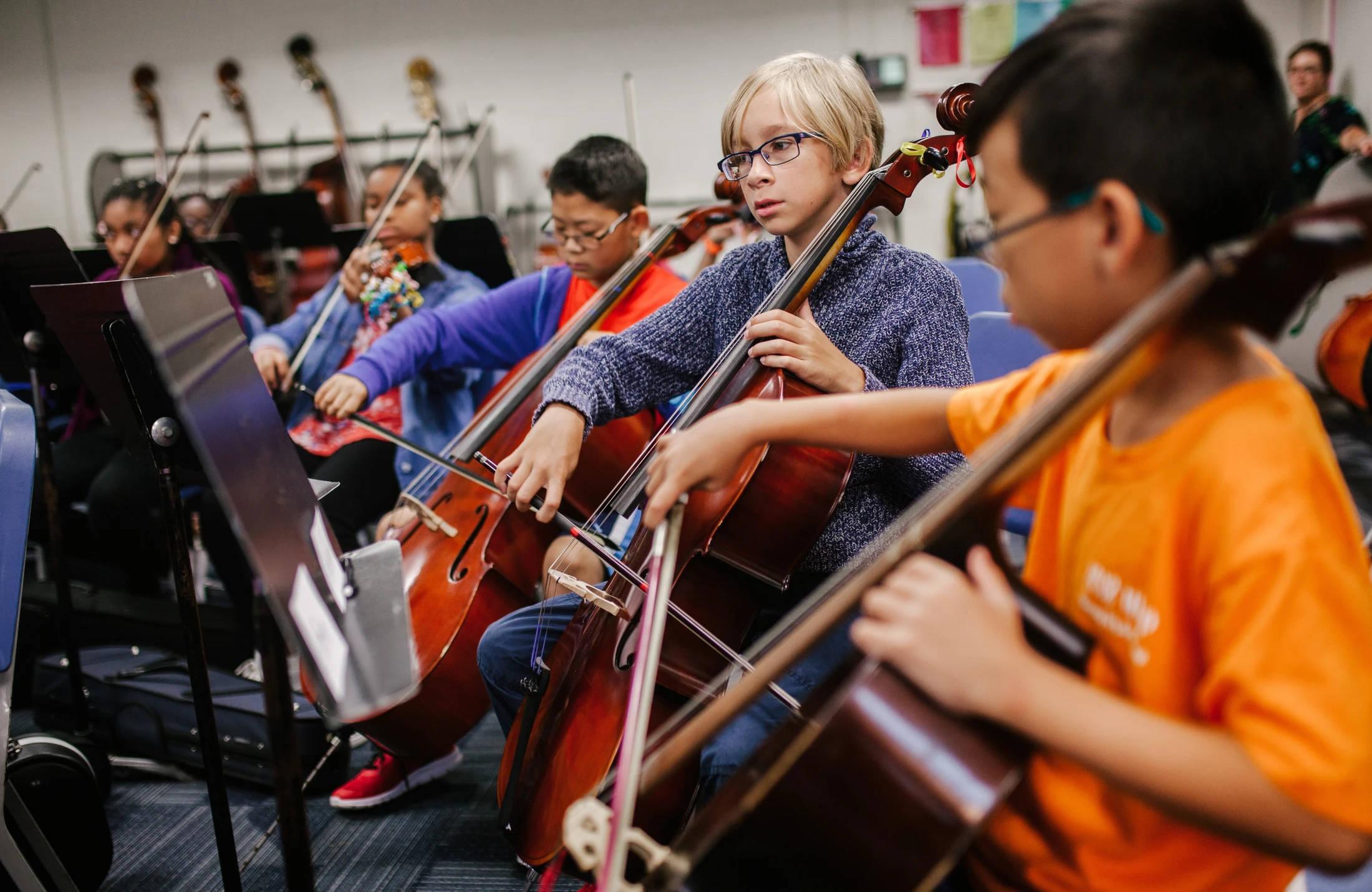 A group of children playing cello in a classroom.
