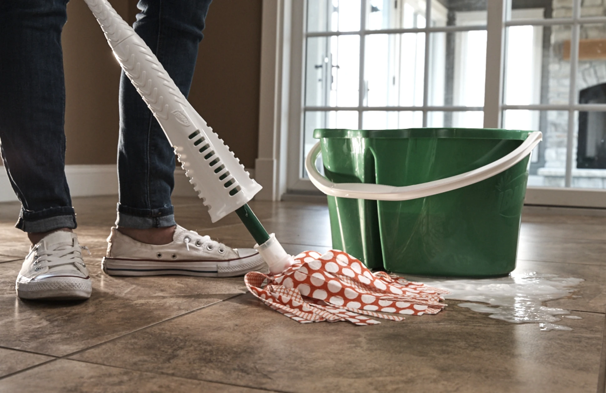 A woman mopping a floor with a mop and bucket.