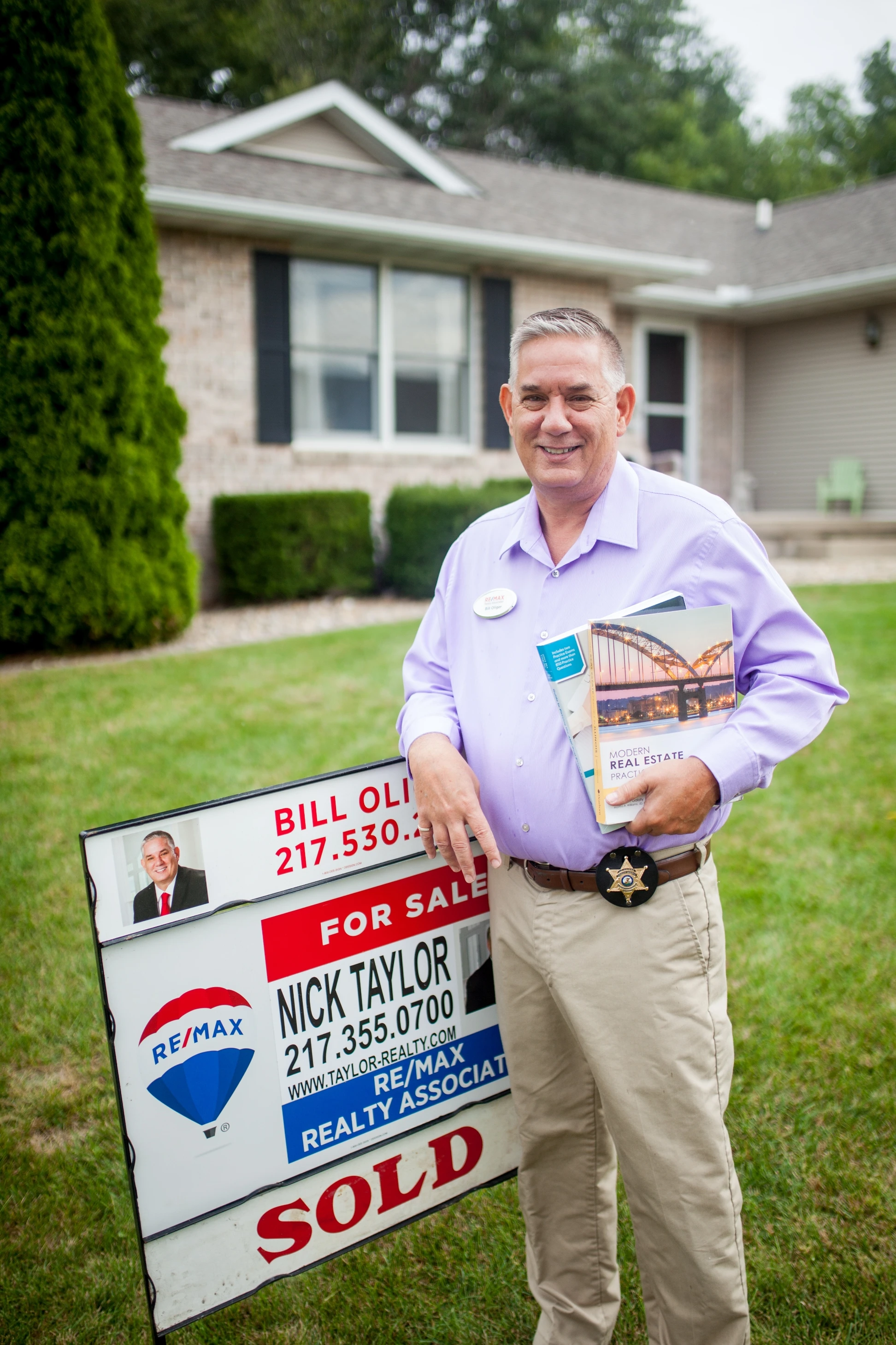 A man standing in front of a house with a sold sign.