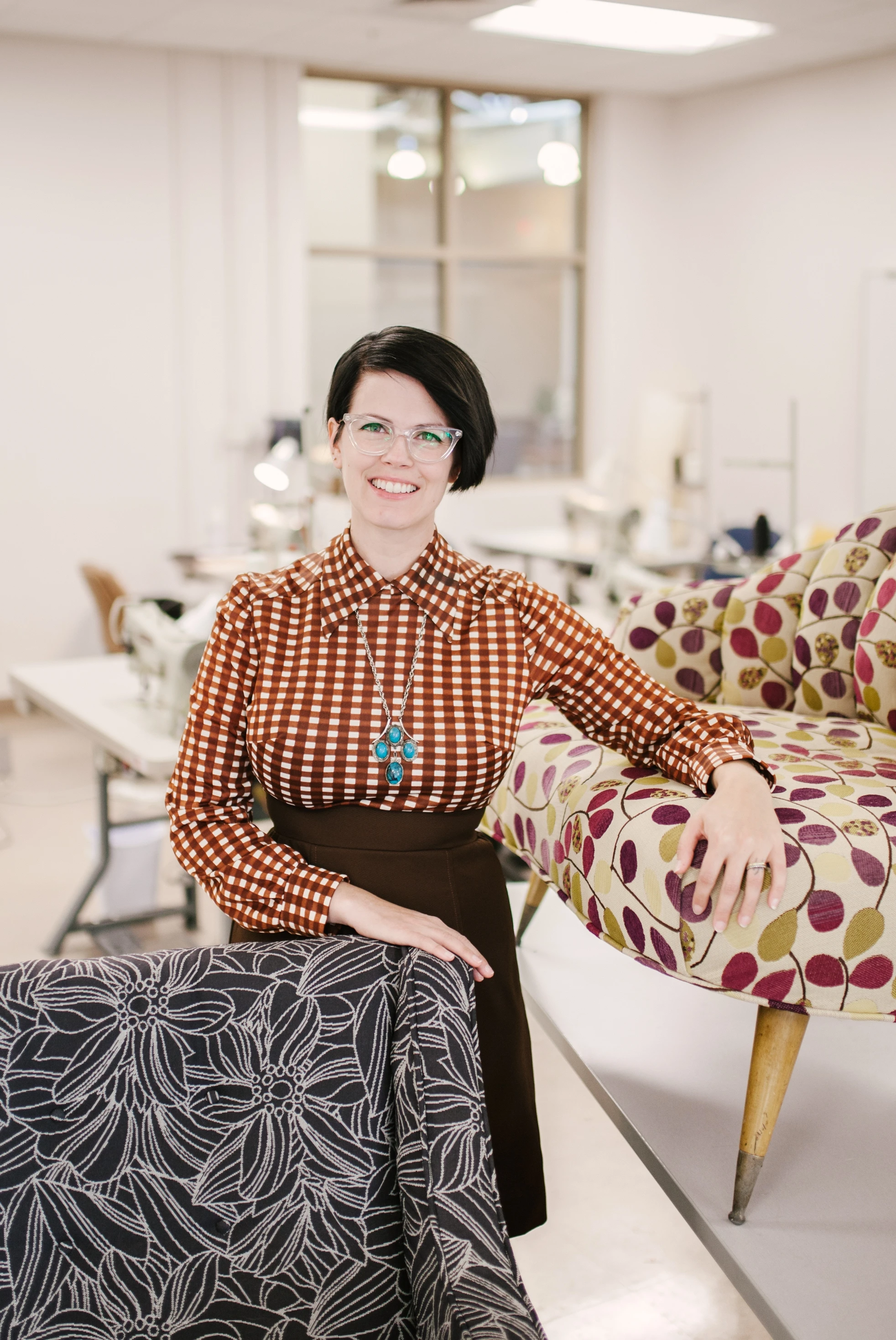 A woman standing in front of a chair in a workshop.