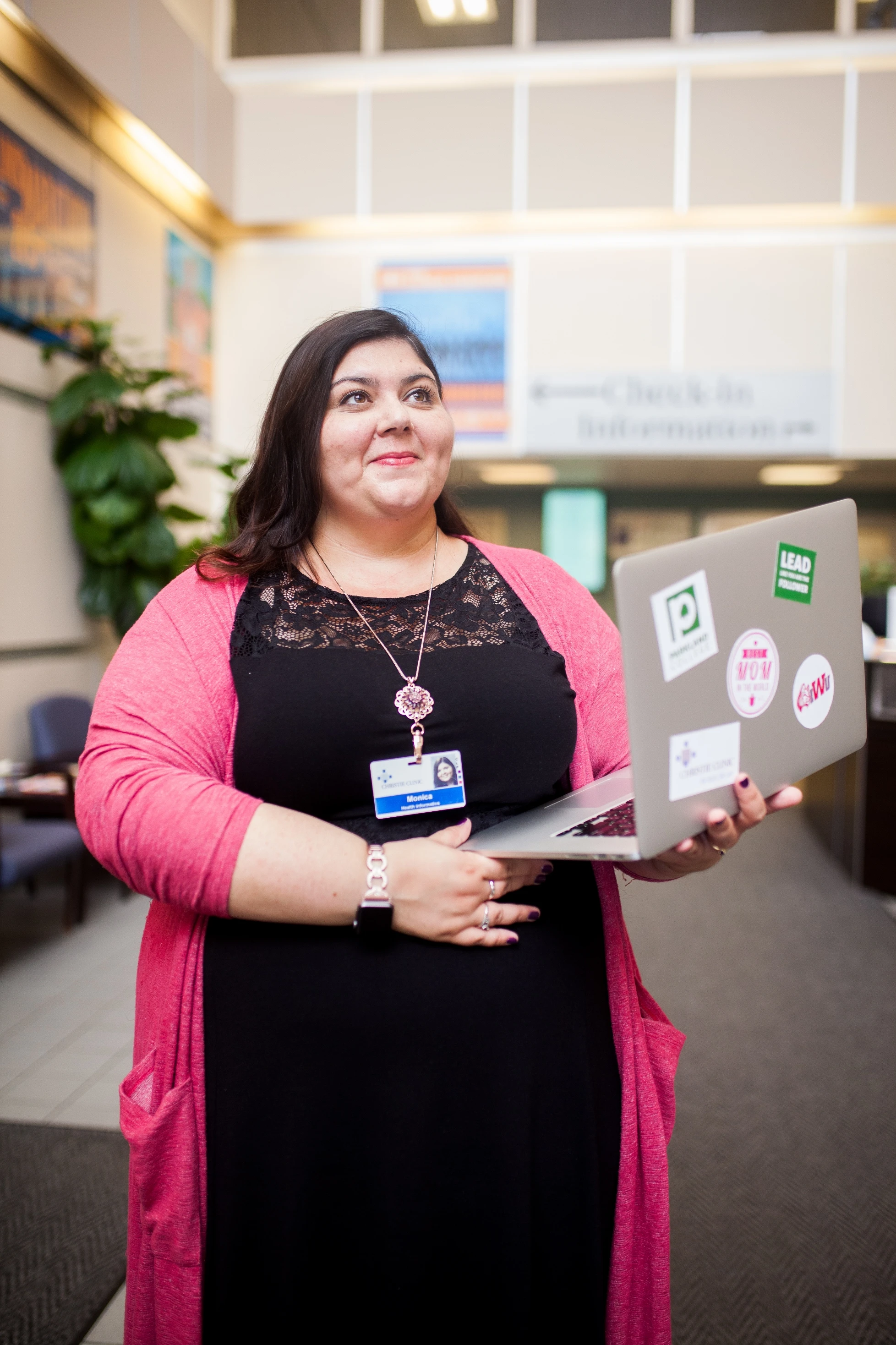 A woman holding a laptop with stickers on it.