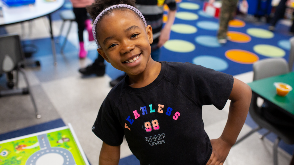 A grade school child smiling in a classroom setting.
