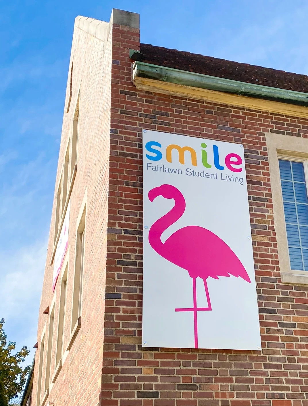 A pink flamingo sits on the side of a building.