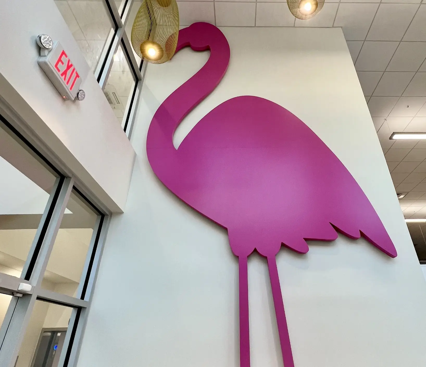 A pink flamingo on the wall of a building.