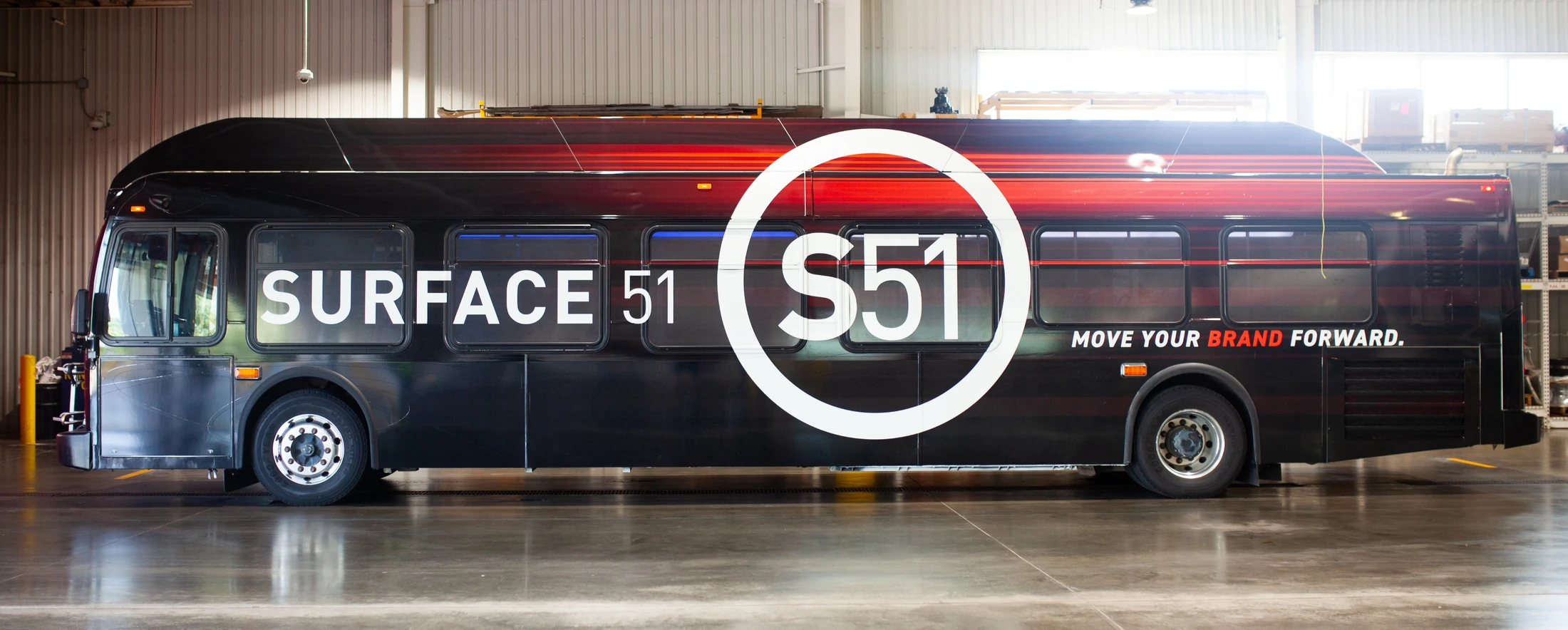 A bus in a warehouse with the words surface 55 on it.
