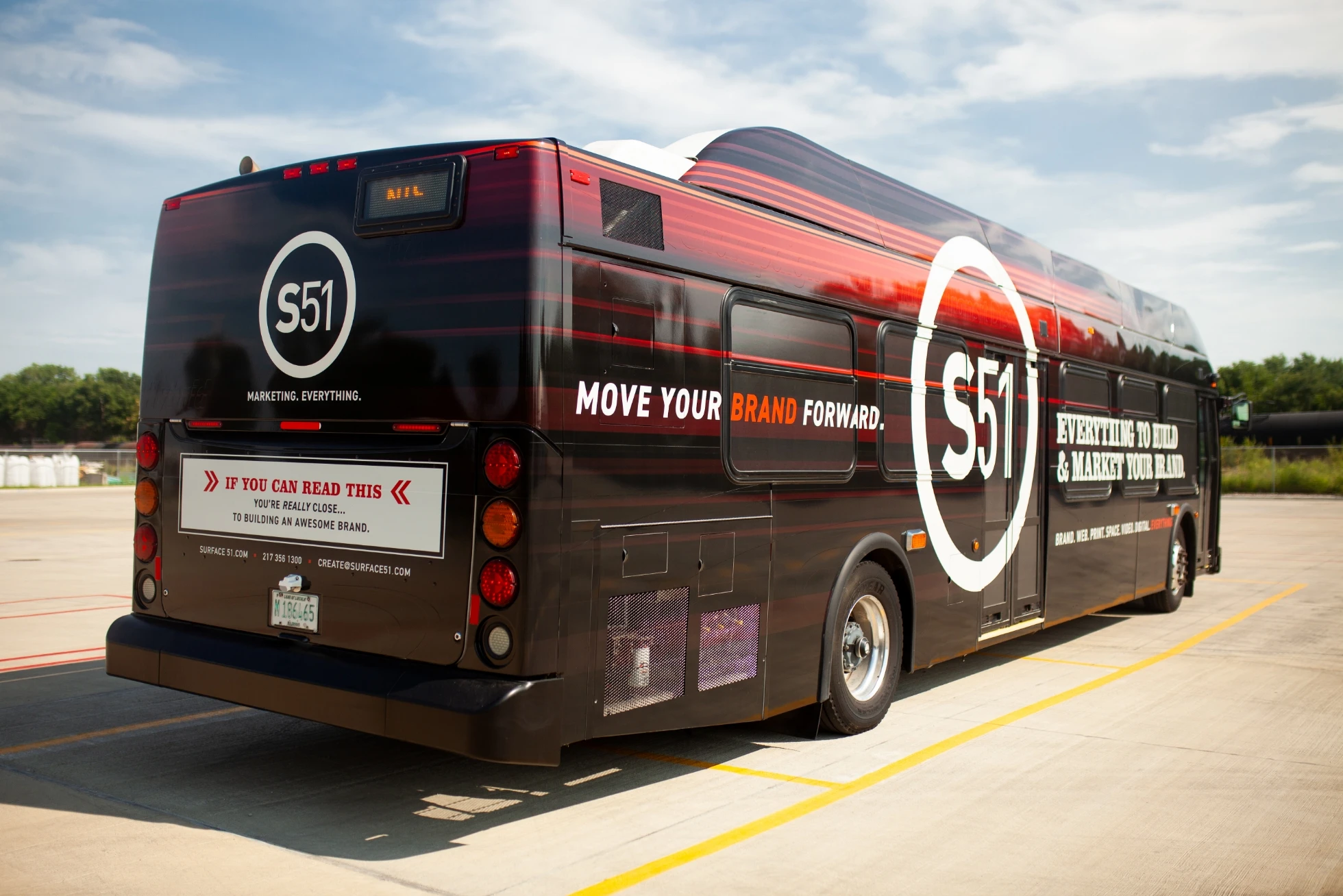 A black and red bus is parked in a parking lot.