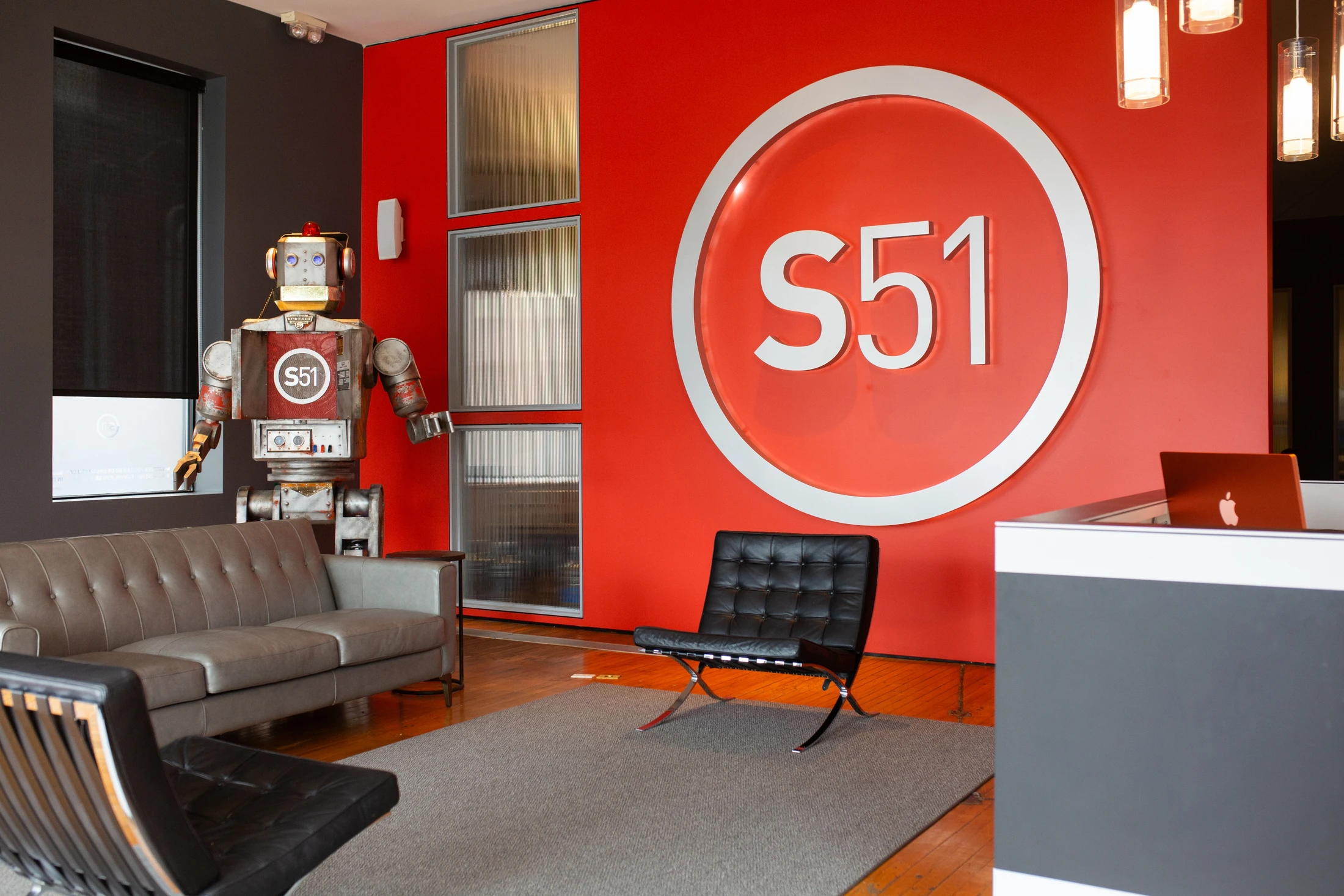 An office with red walls and a robot on the wall.