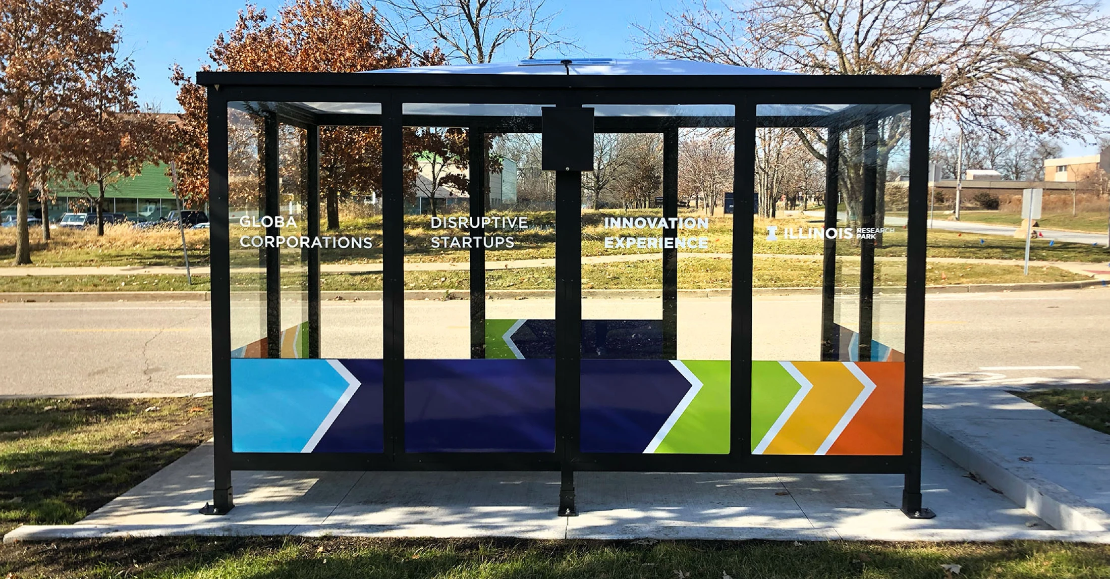 A bus stop with a colorful sign on it.